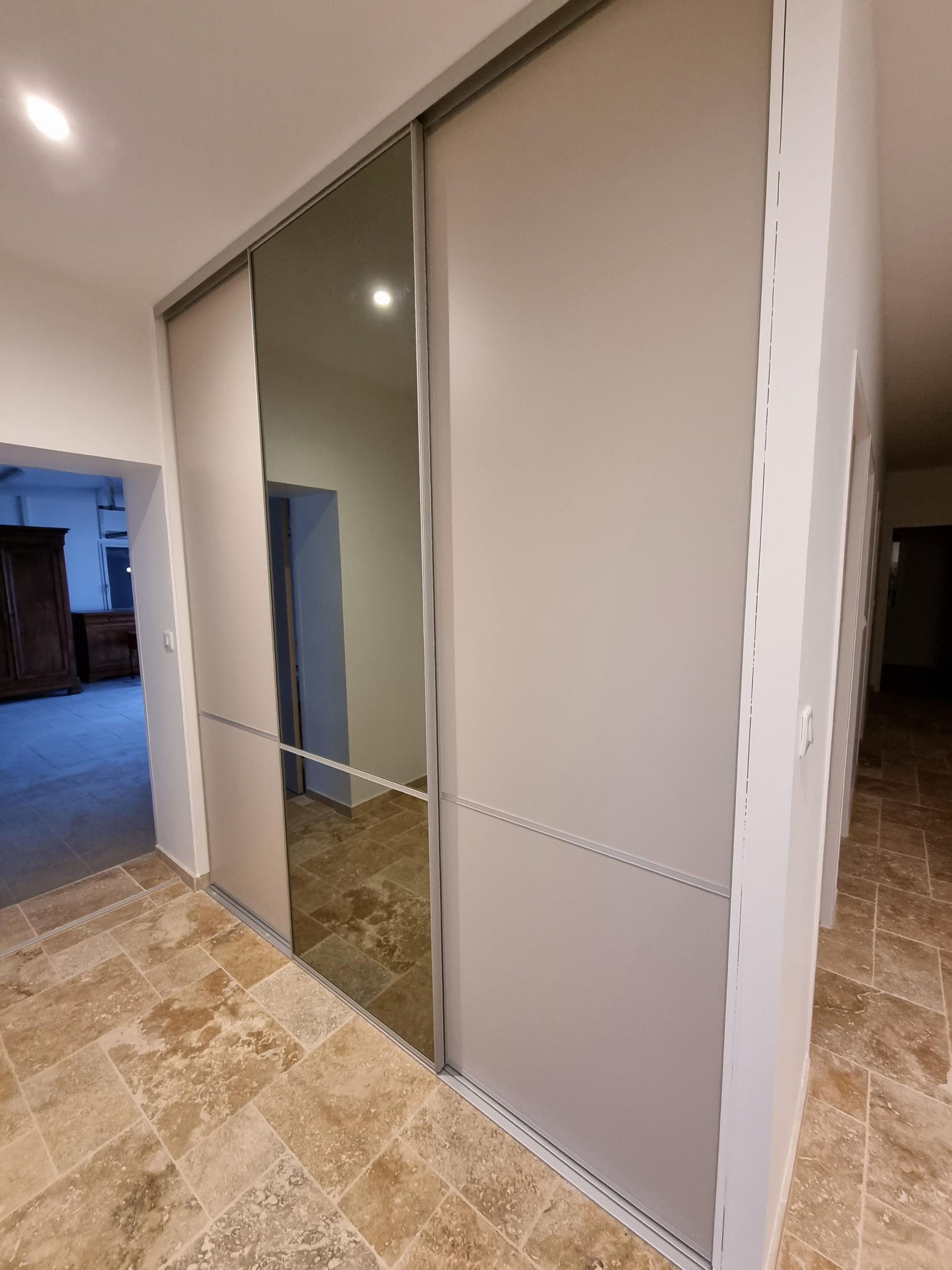 Placard avec portes coulissantes sur rail et miroir intégré, sol en pierre naturelle