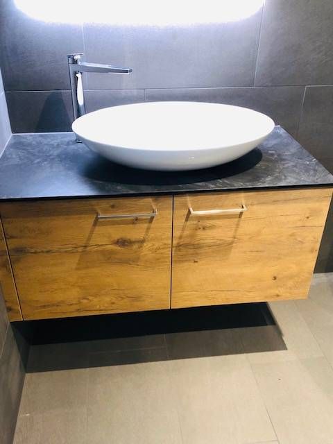 Auf einem schwebenden Waschtisch aus Holz mit zwei Schubladen und einer Arbeitsplatte steht ein weisses Aufsatzwaschbecken.