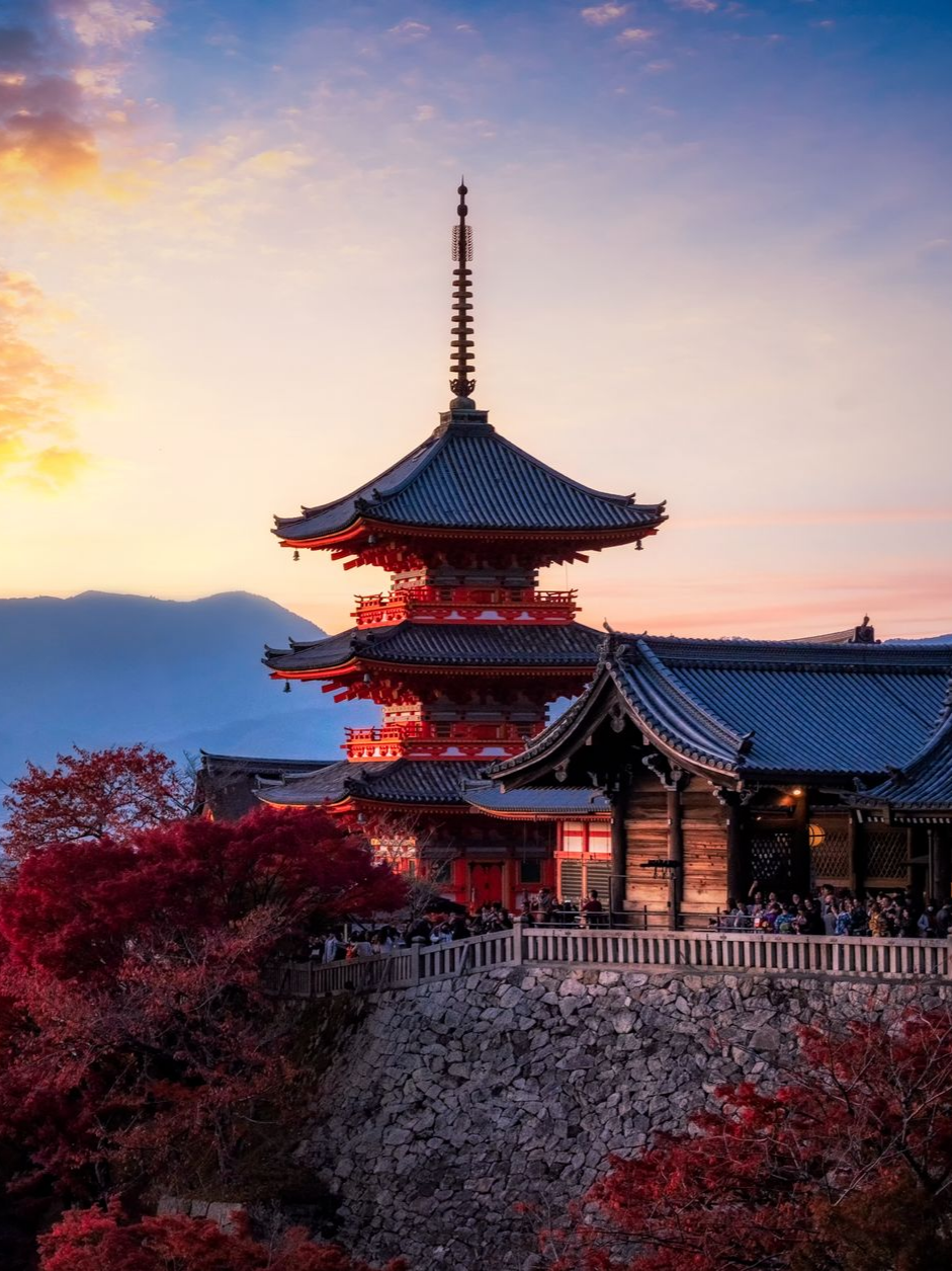 Temple japonais au coucher du soleil avec des feuilles rouges.