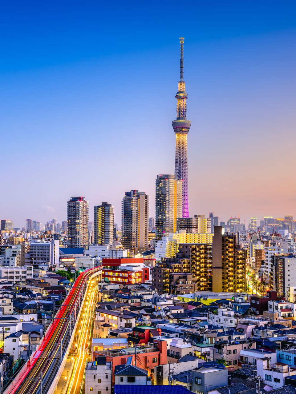 Paysage urbain de Tokyo avec la Tokyo Skytree dominant l'horizon, voie ferrée rouge au premier plan.