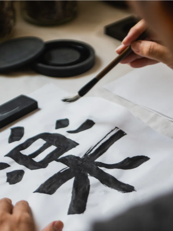 Papier de calligraphie avec des caractères chinois sur un bureau, stylo dessus.