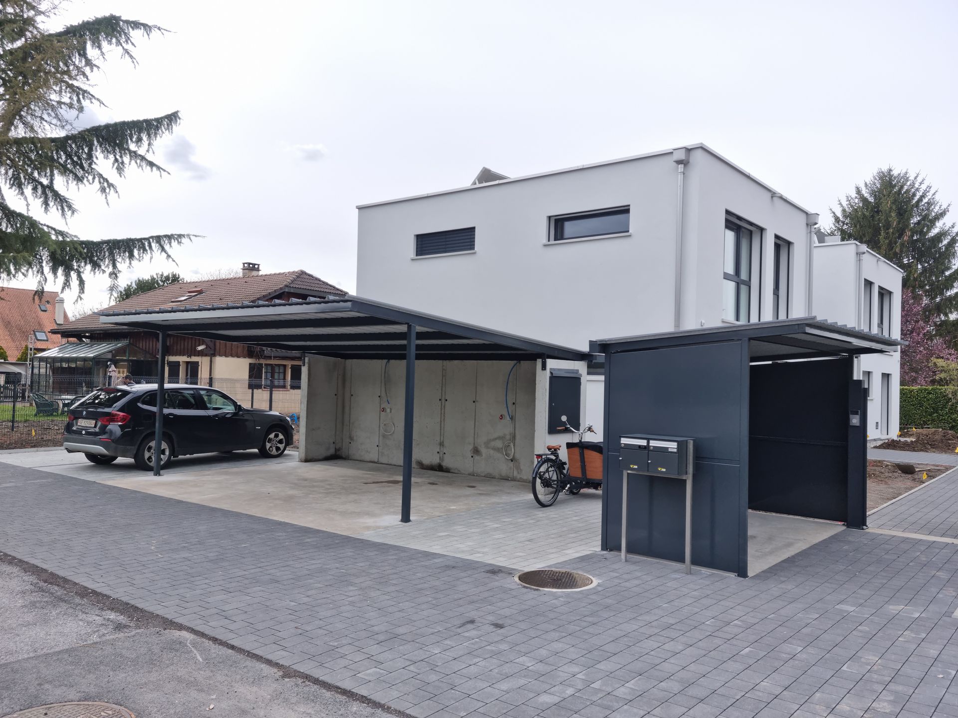 Pergola positionnée au-dessus d'un parking en béton
