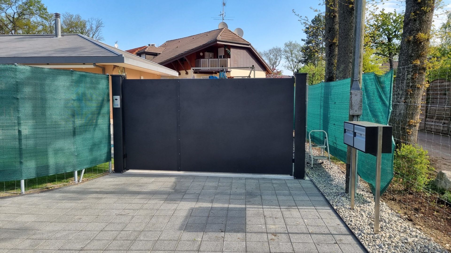 Pose d'un portail noir coulissant en aluminium avec des clôtures vertes