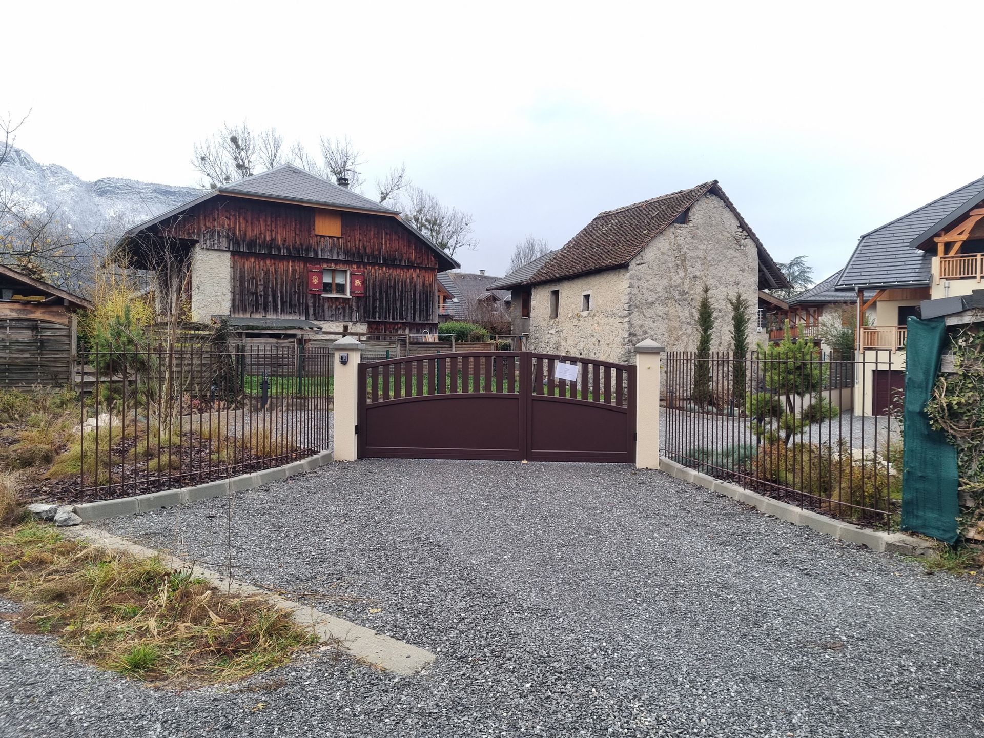 Pose d'un portail en aluminium de couleur brune devant une allée de graviers
