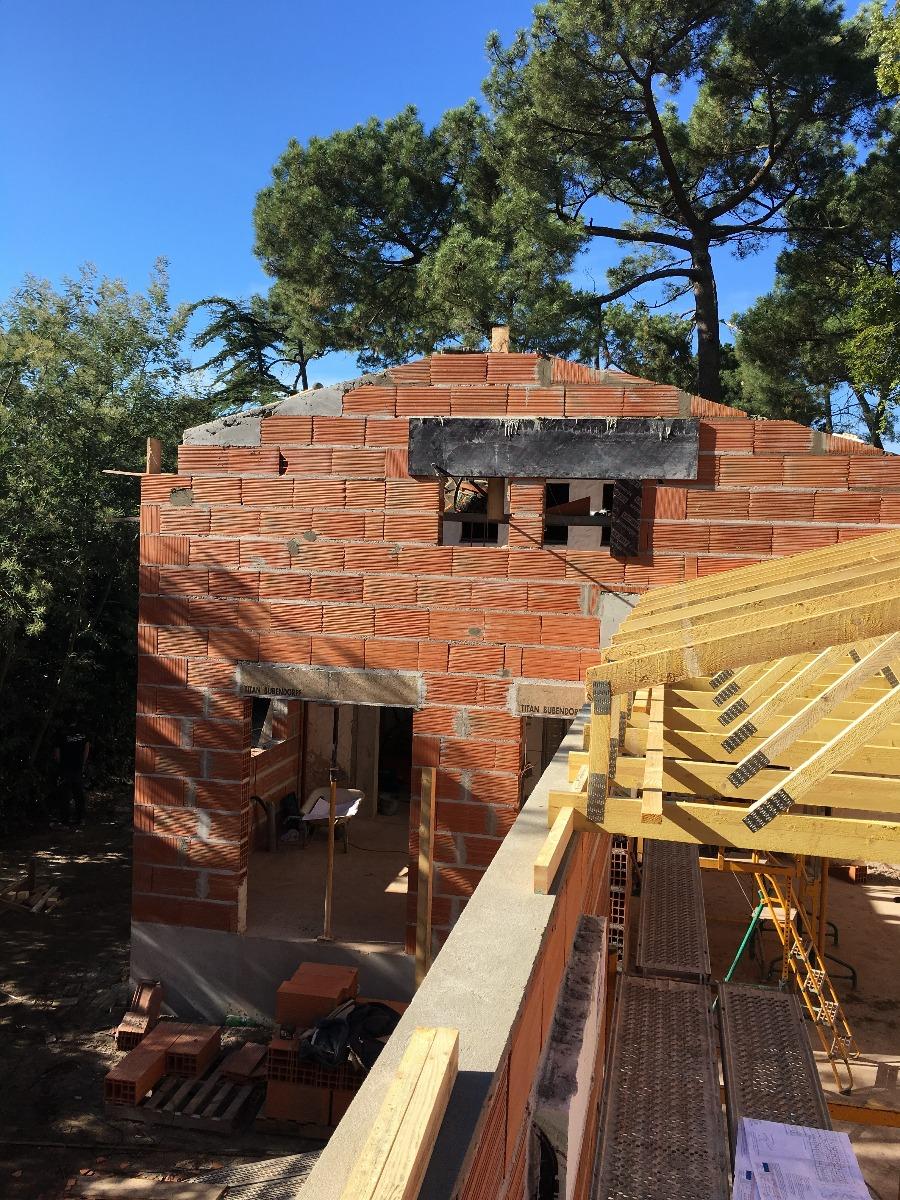 Maison en brique en cours de construction avec pièces de menuiserie sur le toit