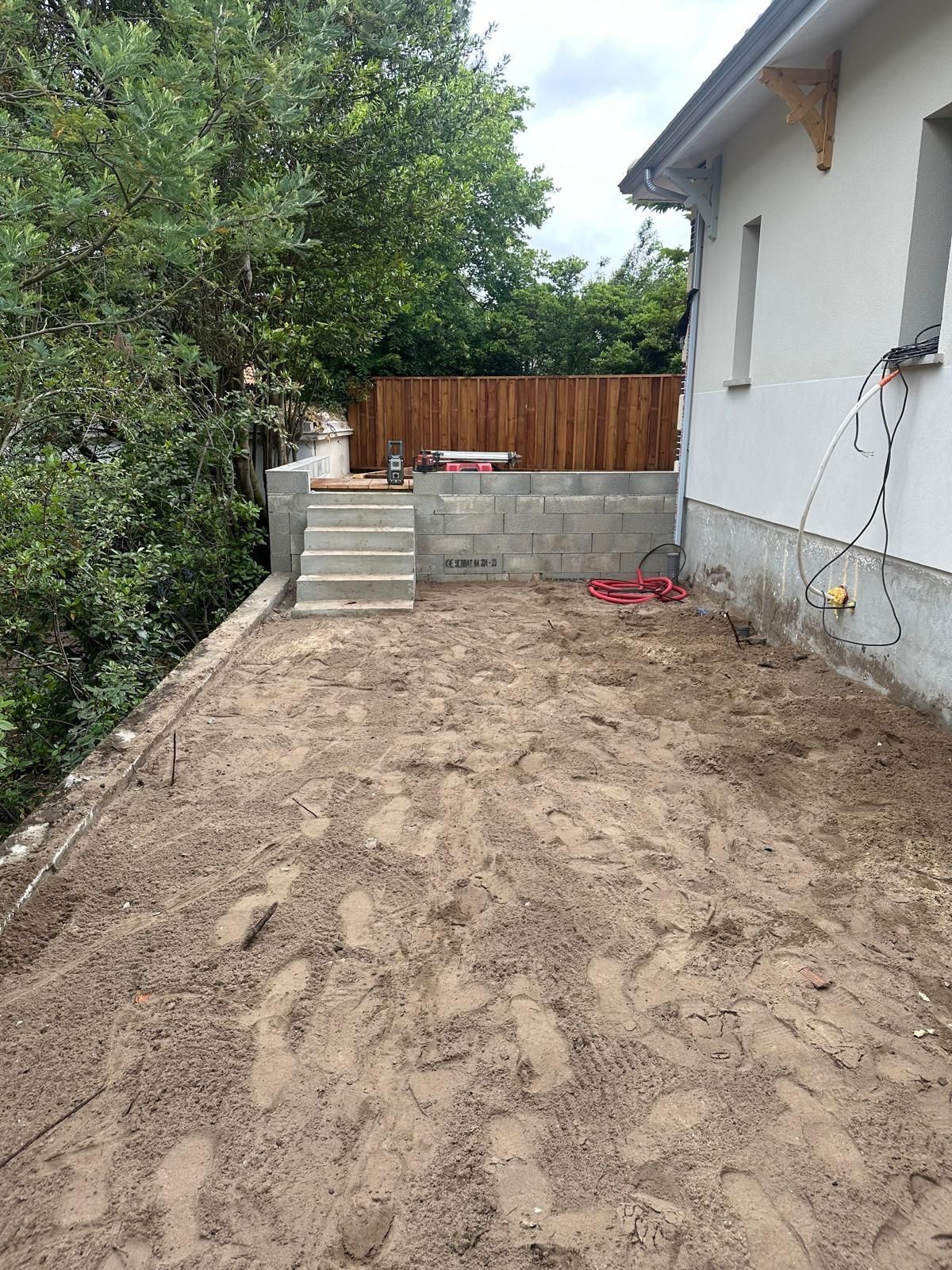 Photo de la réalisation d'un petit escalier de béton à côté d'une façade blanche 