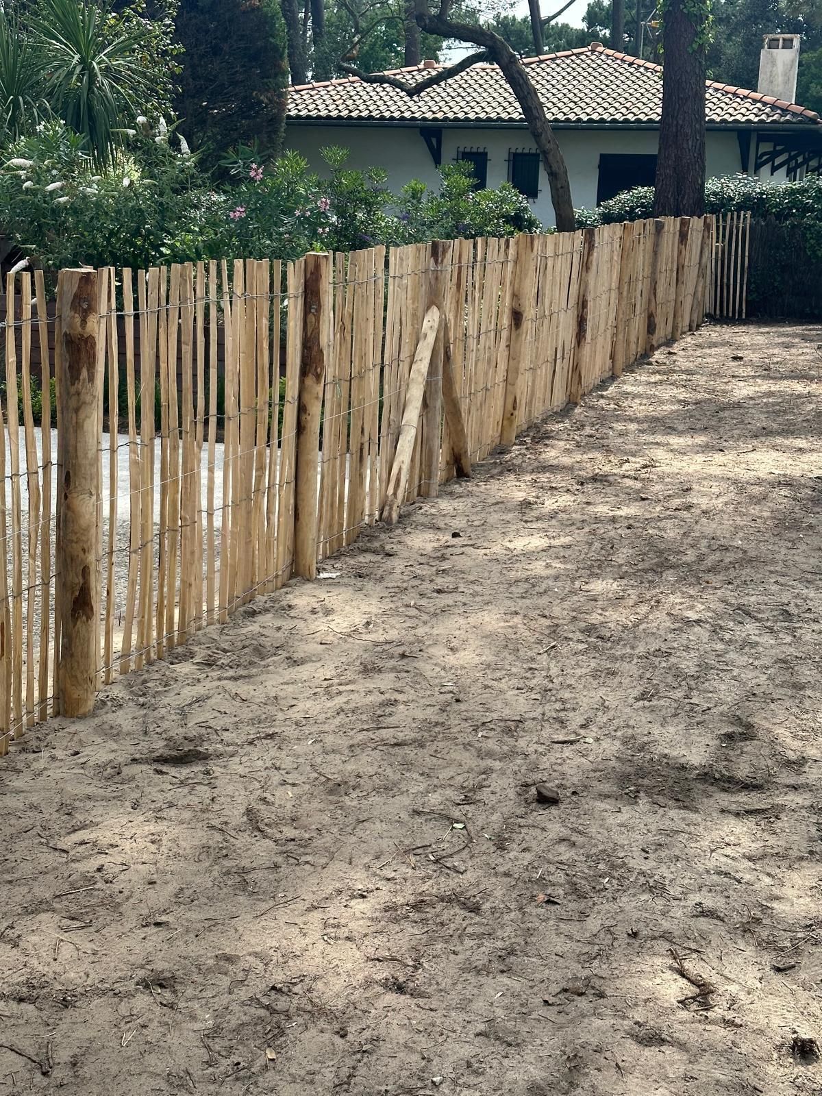 Détail d'une clôture réalisée en bois et reliée par des fils de fer 