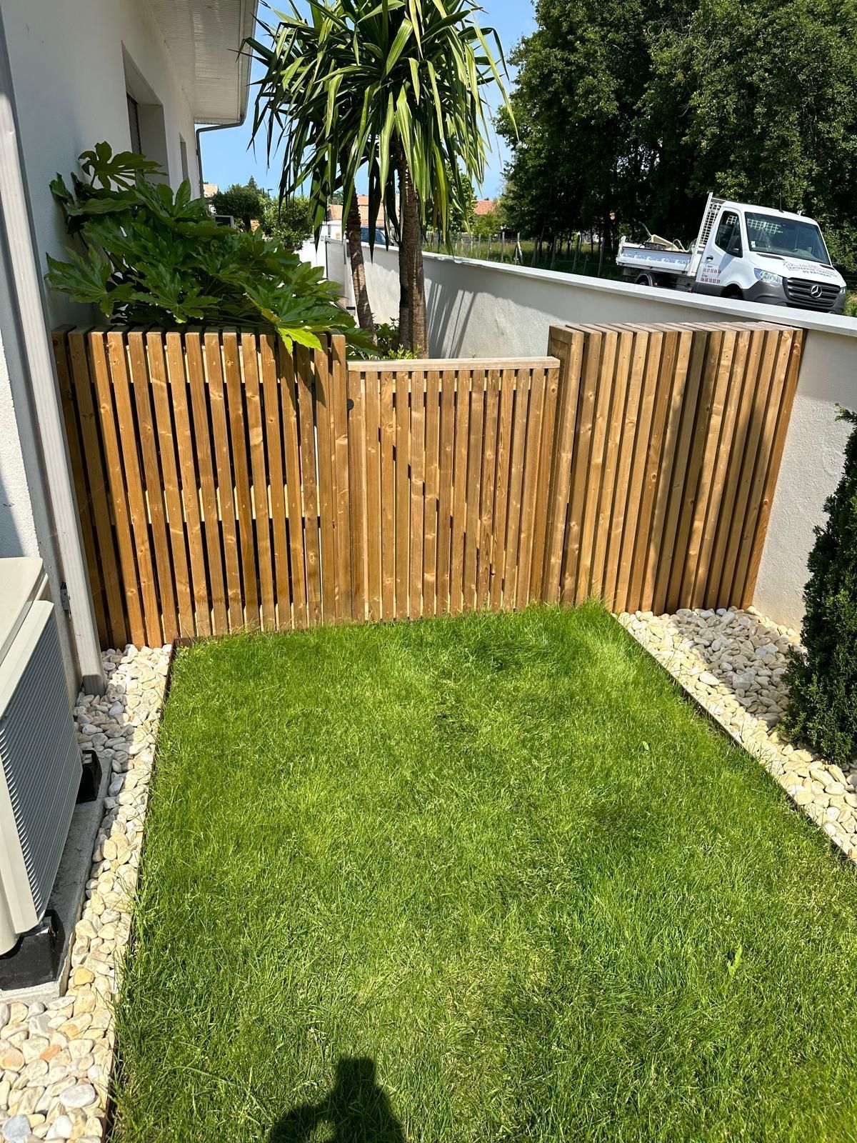 Clôture en bois devant un gazon entouré de pierres blanches 