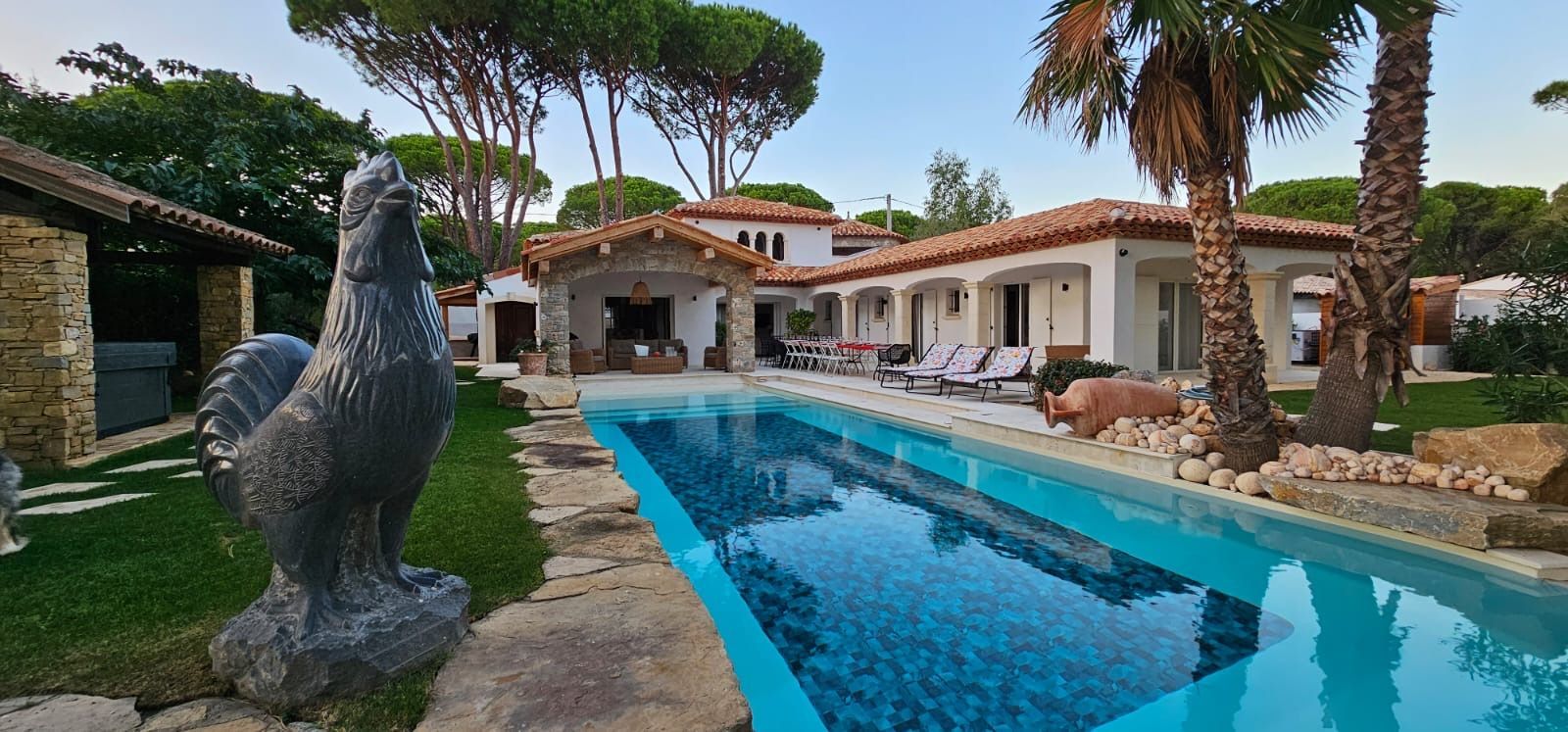 Une villa avec une piscine creusée et une statue de coq