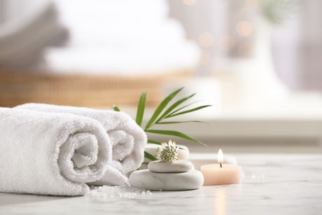 Serviettes de bains blanches, une bougie et des galets
