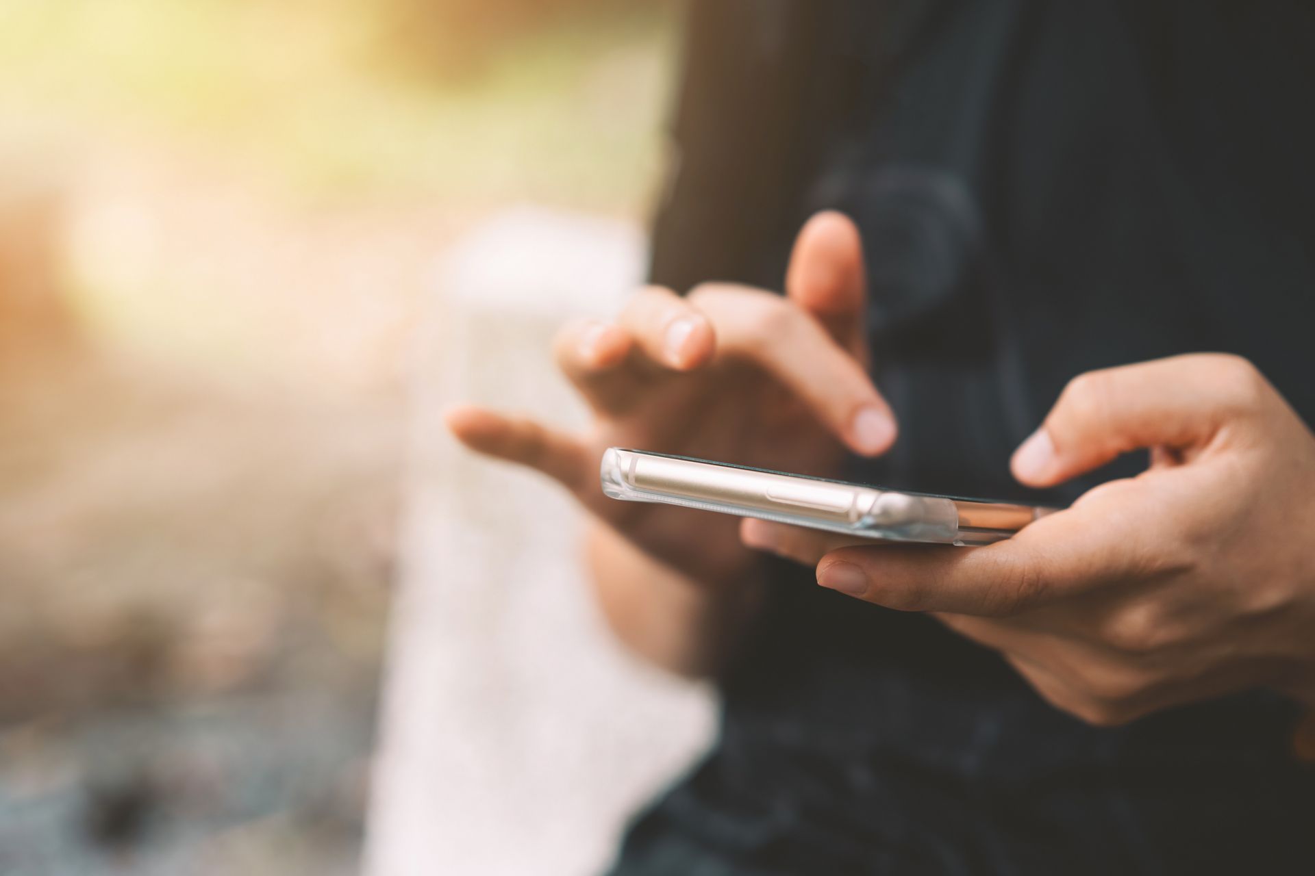 Person hält ein Smartphone und tippt oder wischt mit den Fingern über den Bildschirm.