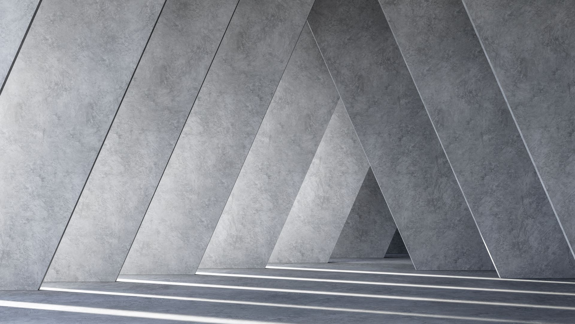 Grauer dreieckiger Betonbogen mit Licht- und Schattenspiel.