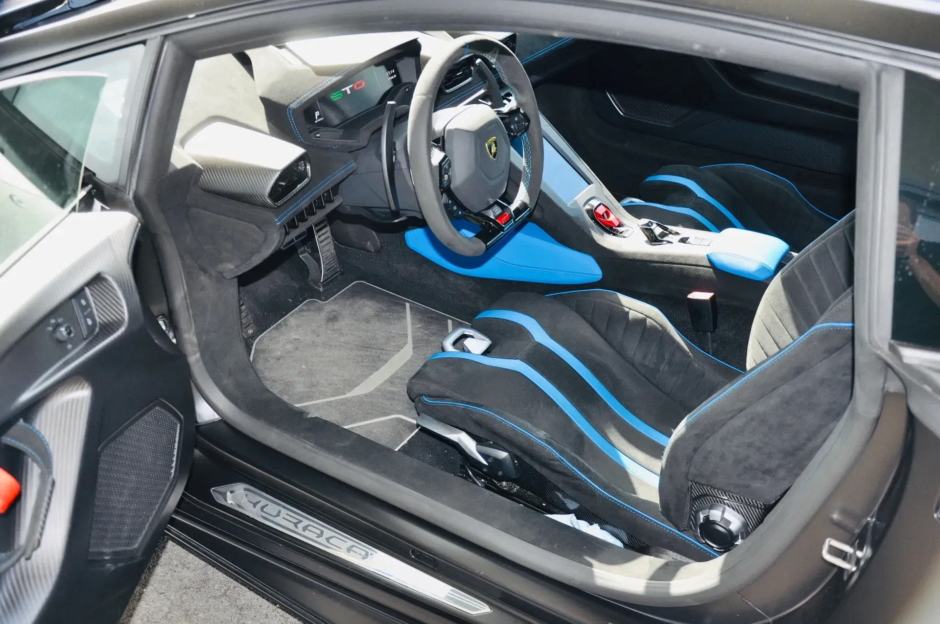 Intérieur Lamborghini noir avec des touches de bleu sur les sièges, le tableau de bord, les portières, le volant.