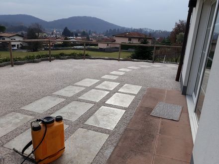 Ampio loft vuoto con pavimento in legno chiaro, pareti bianche e scala in metallo accanto a una parete divisoria in legno.