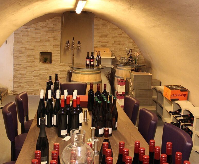 Flaschen Wein stehen aufgereiht auf einem Tisch in einem Weinkeller