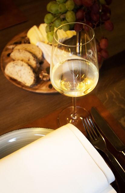 Ein Glas Wein steht auf einem Tisch neben einem Teller mit Essen