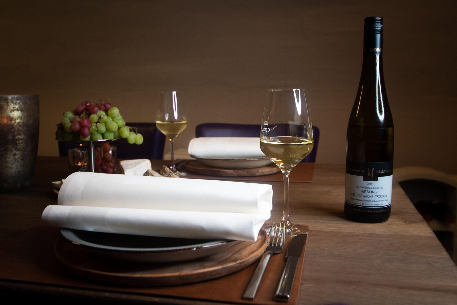 Eine Flasche Wein steht auf einem Holztisch mit Tellern und Gläsern Wein.