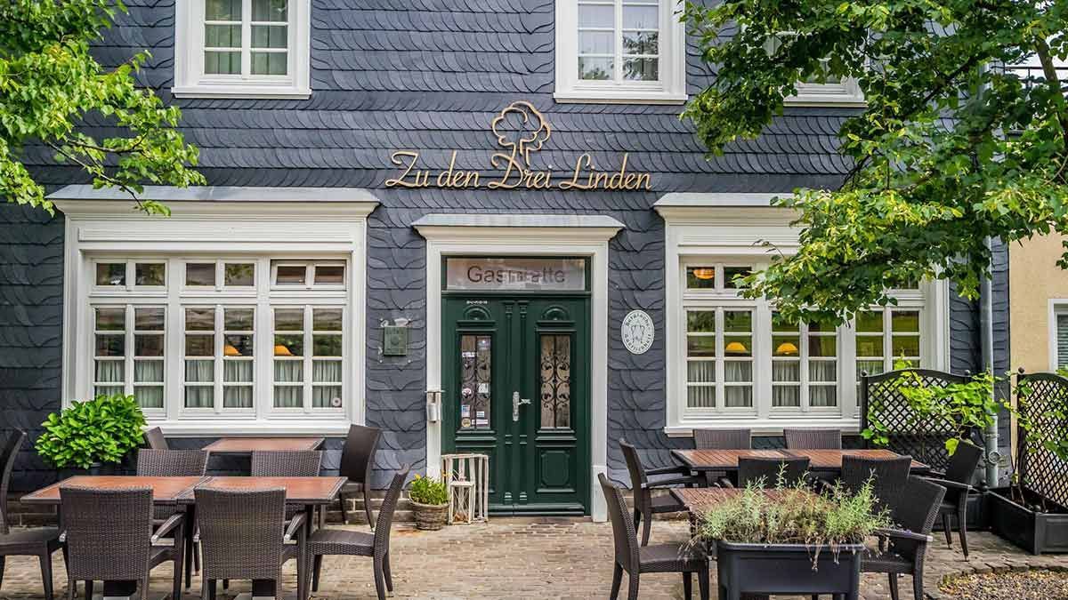 Ein großes Gebäude mit Tischen und Stühlen davor.