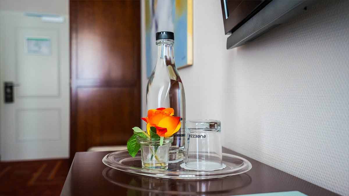 Eine Flasche Wasser und ein Glas auf einem Tablett auf einem Tisch.