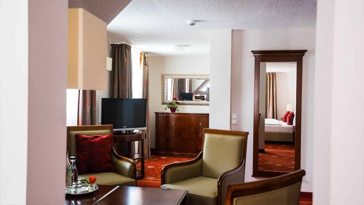 Ein Wohnzimmer mit Stühlen, einem Tisch, einem Fernseher und einem Spiegel.