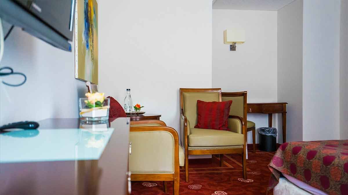 Ein Hotelzimmer mit Bett, Stuhl, Schreibtisch und Fernseher.