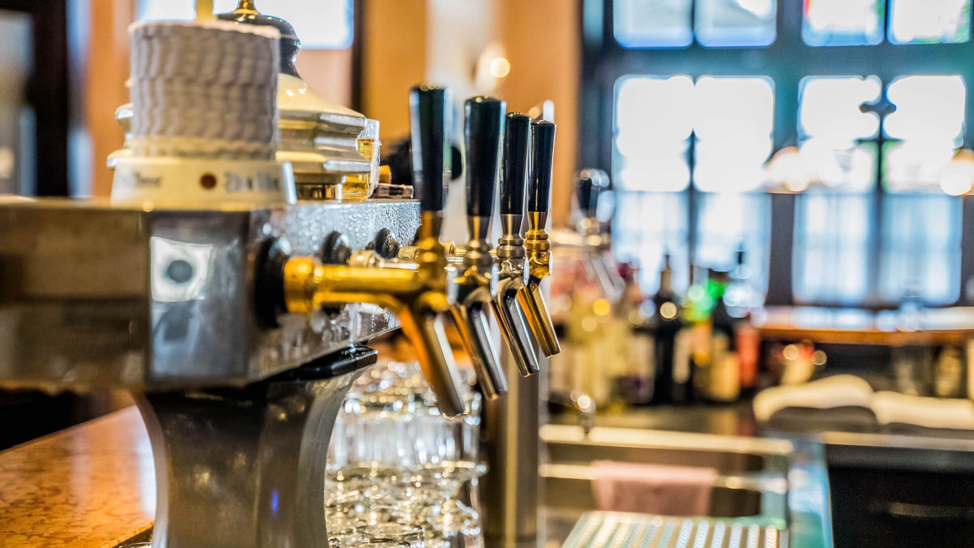 Eine Bar mit vielen Zapfhähnen und Gläsern auf der Theke.
