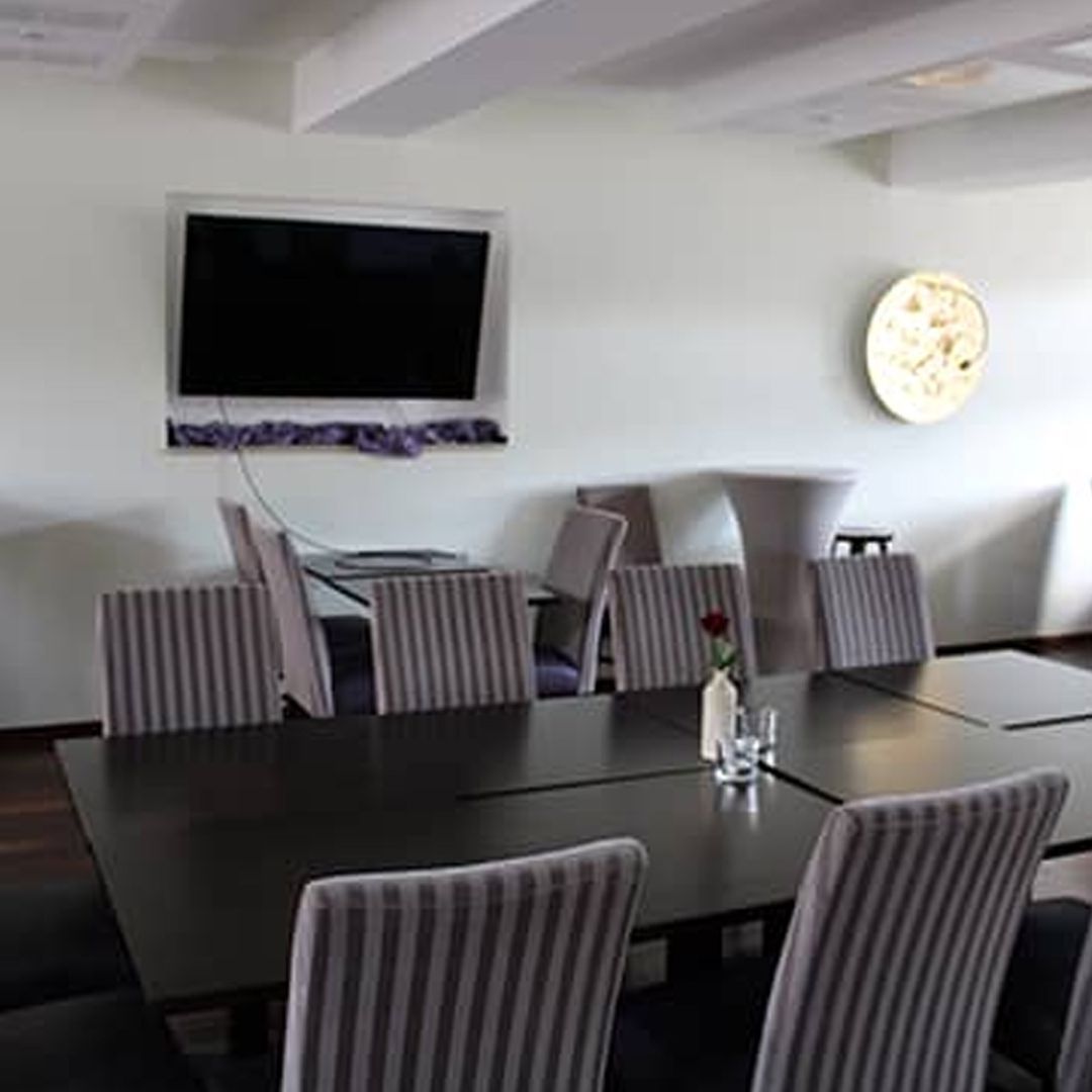 Ein Esszimmer mit Tischen und Stühlen und einer Uhr an der Wand