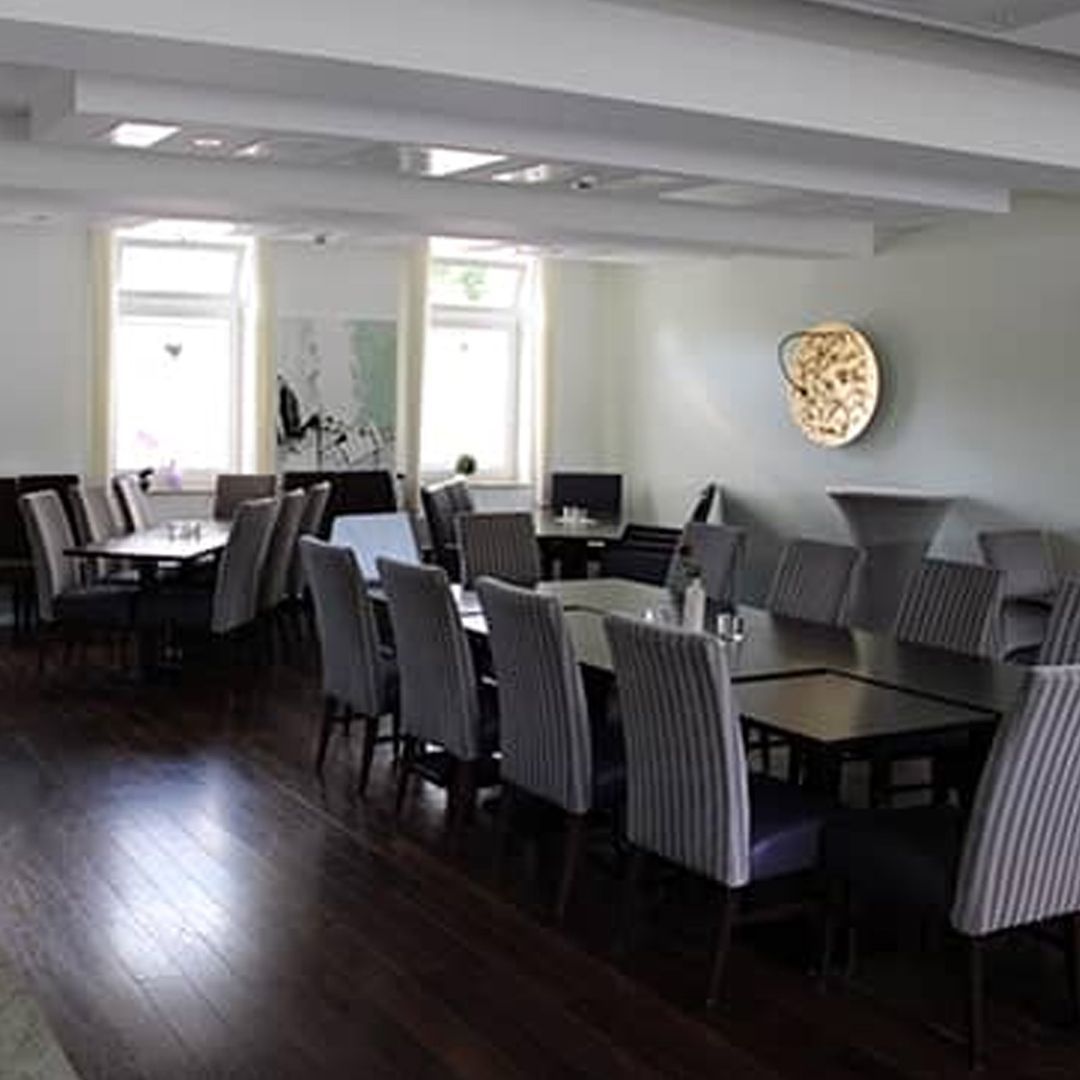 Ein großer Raum mit Tischen und Stühlen und einer Uhr an der Wand