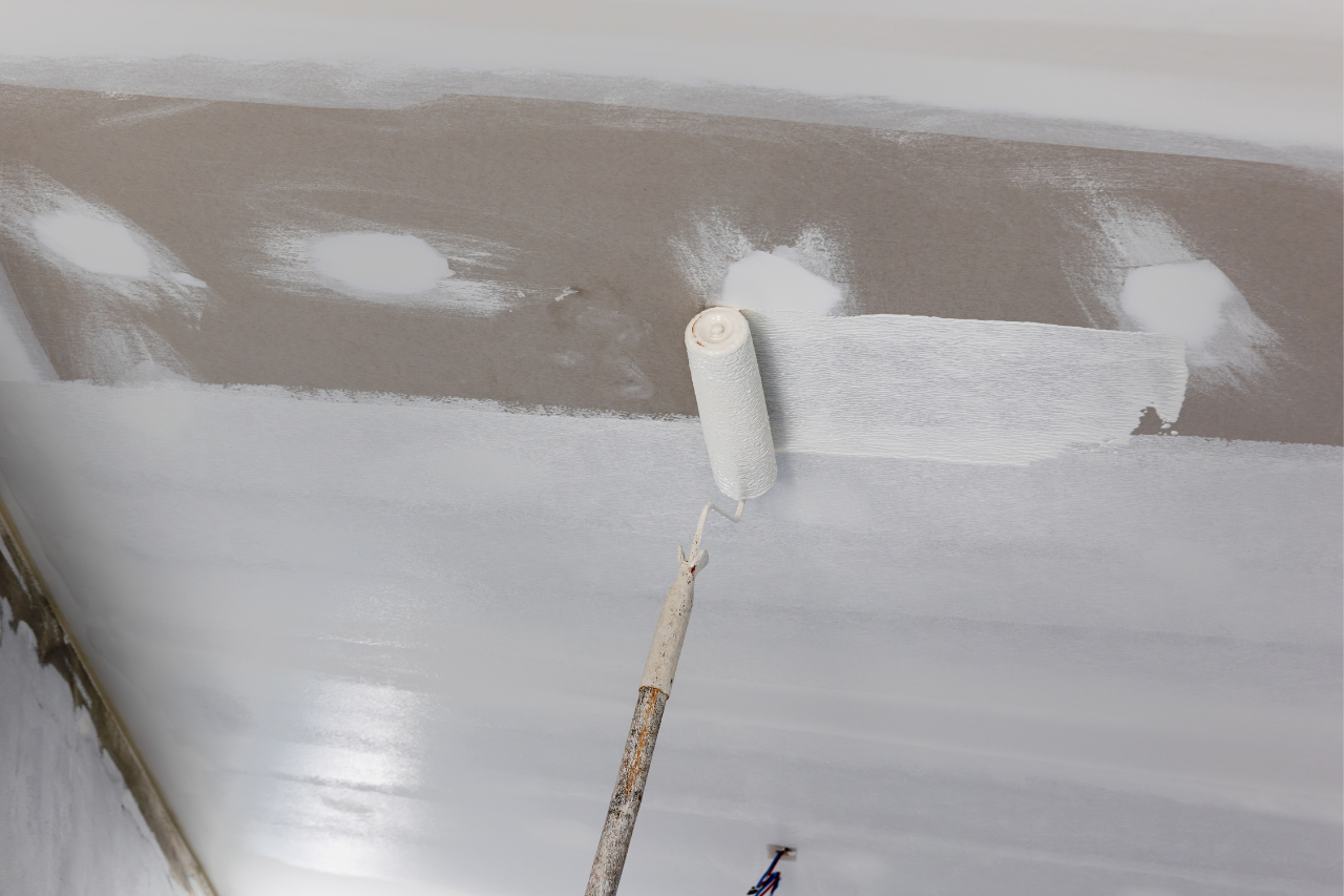 Application de peinture blanche au rouleau sur un plafond.