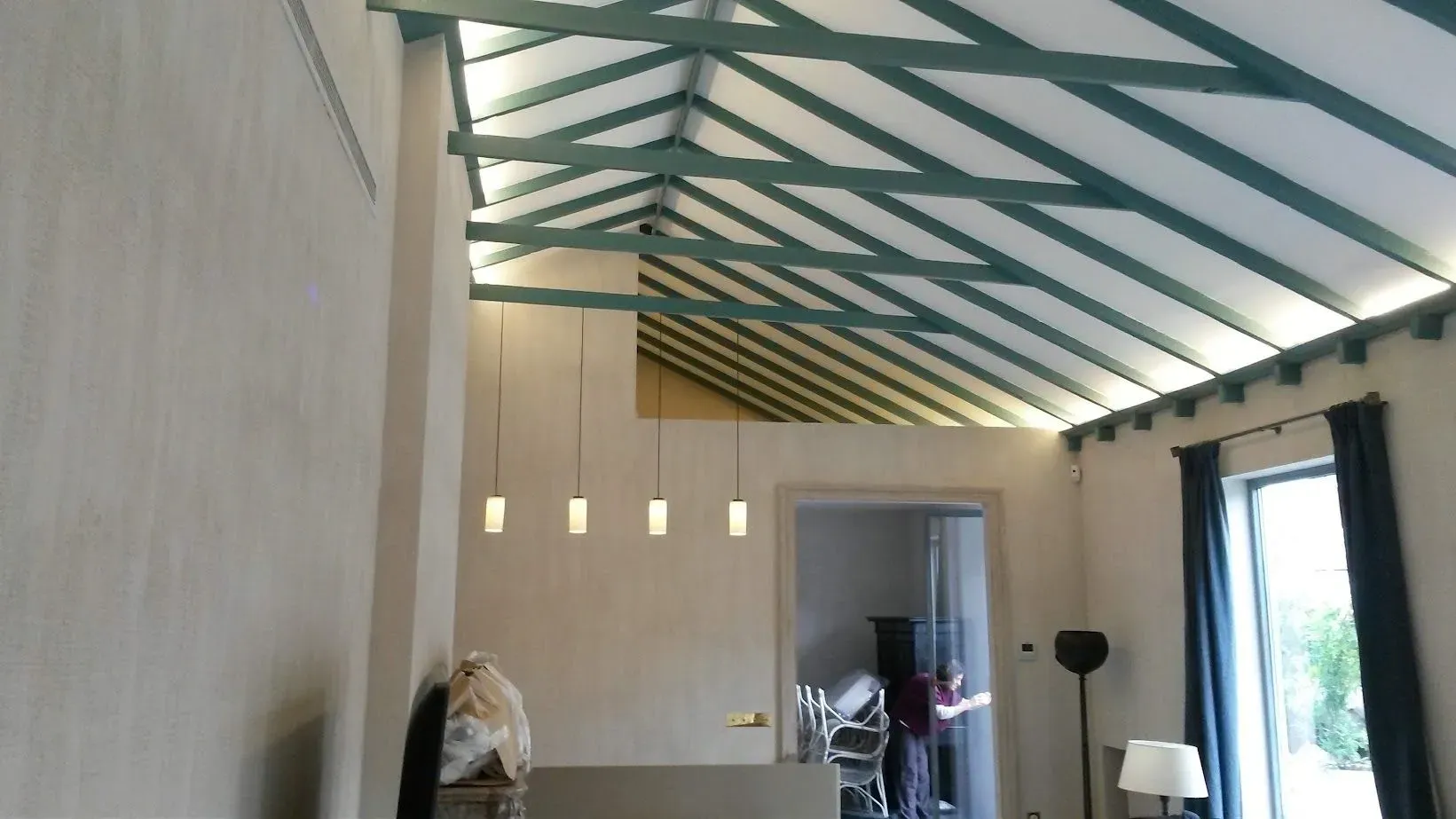 Una sala de estar con un techo con vigas verdes.