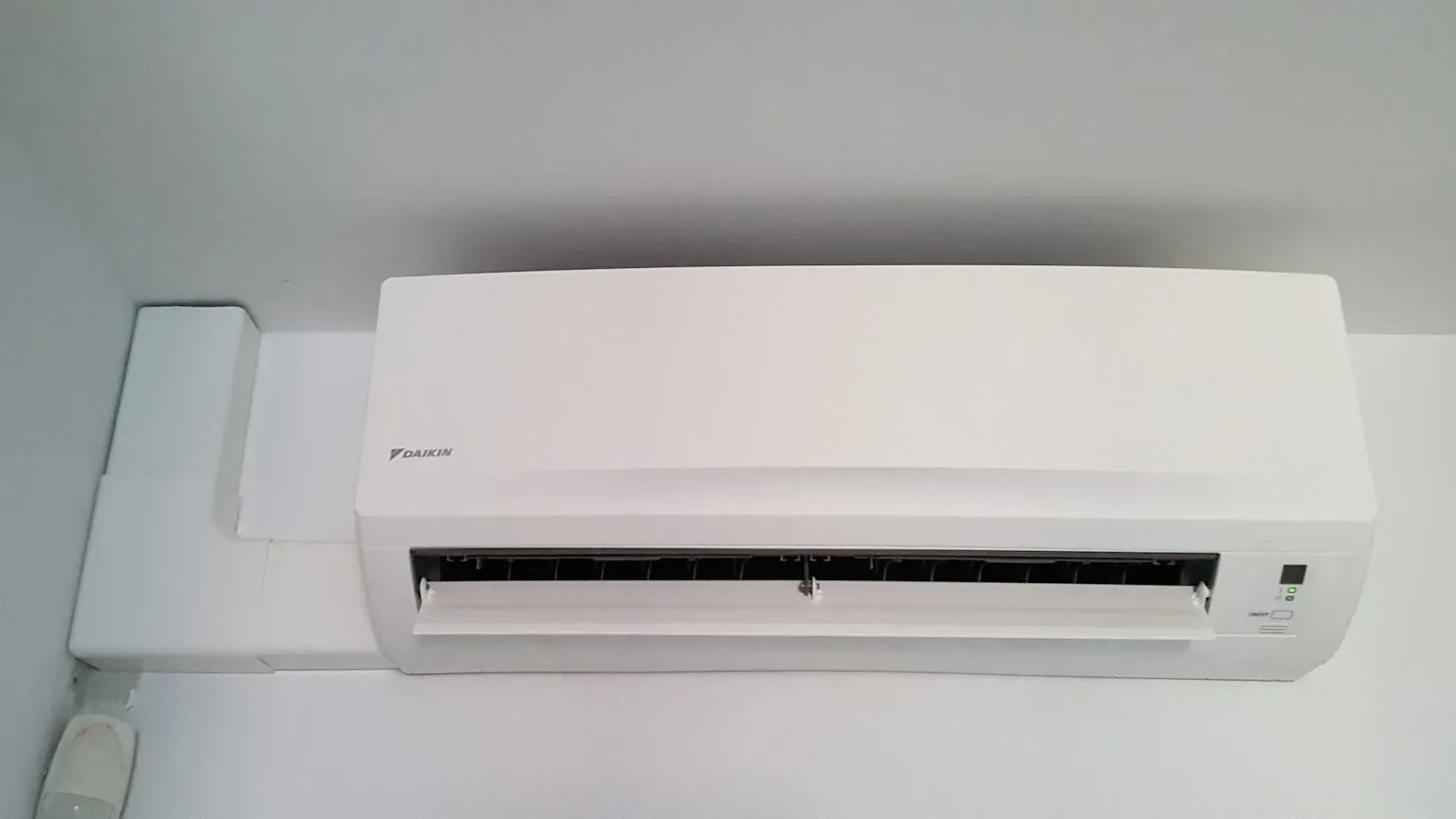 Un acondicionador de aire blanco cuelga del techo de una habitación.