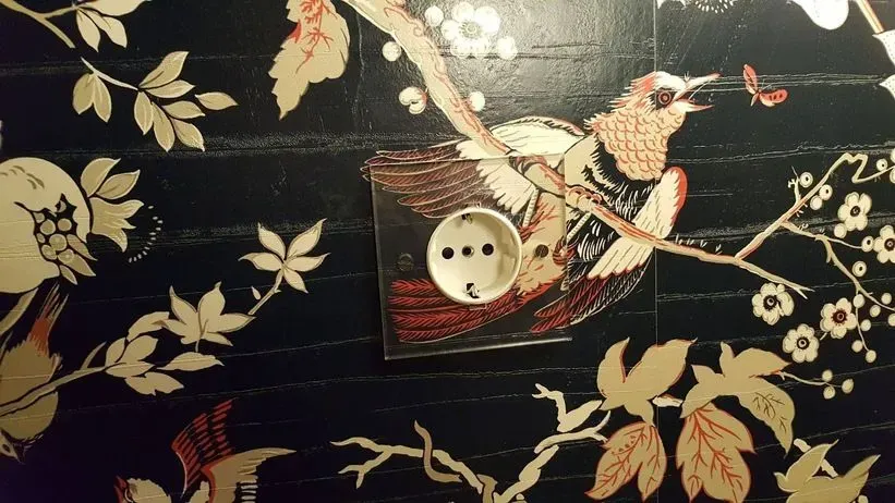 Una pared con un pájaro y flores.