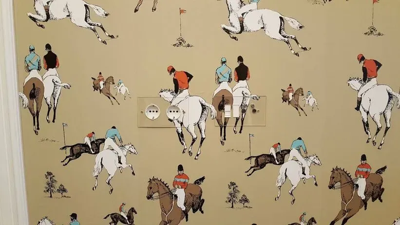 Una pared con un patrón de personas montando a caballo.