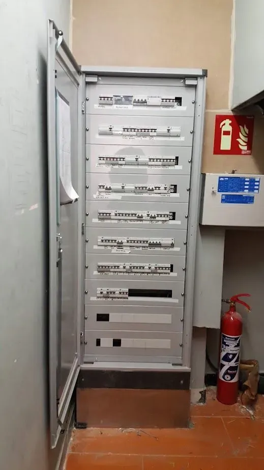Un extintor de incendios está junto a una gran caja eléctrica en una habitación.