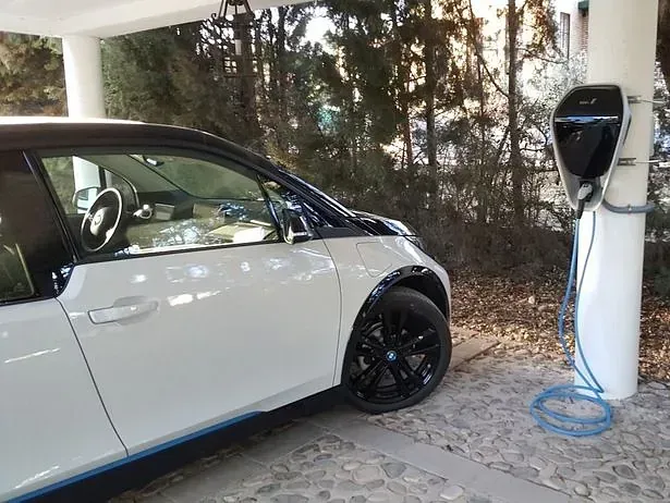 Un coche eléctrico blanco se está cargando en una estación de carga.
