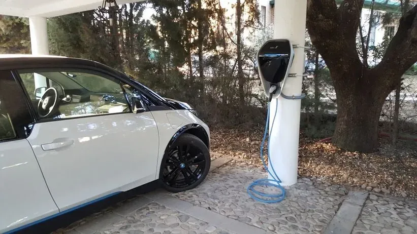Un coche eléctrico blanco se está cargando en una estación de carga.