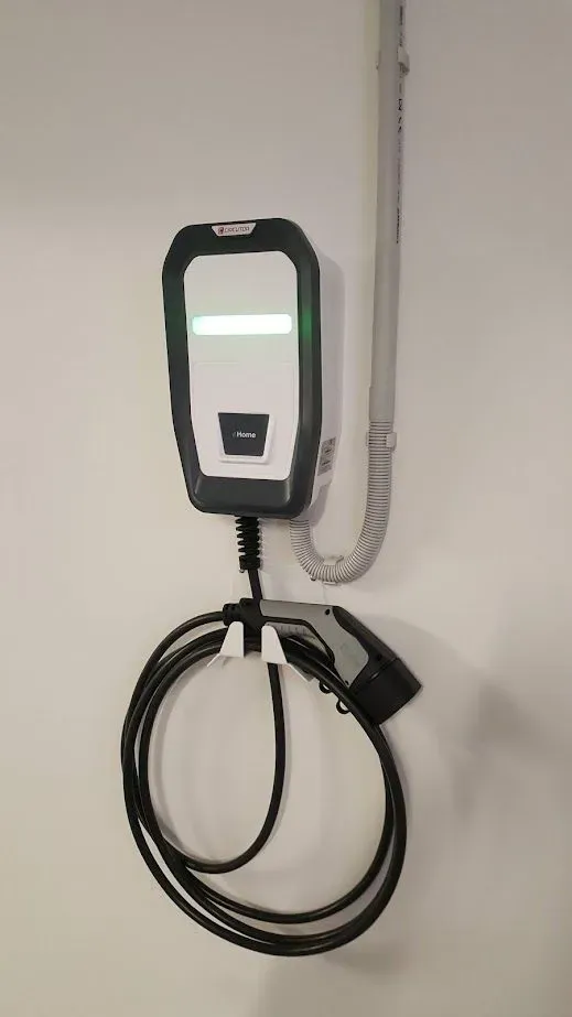 Un cargador de coche eléctrico blanco y negro está colgado en una pared.