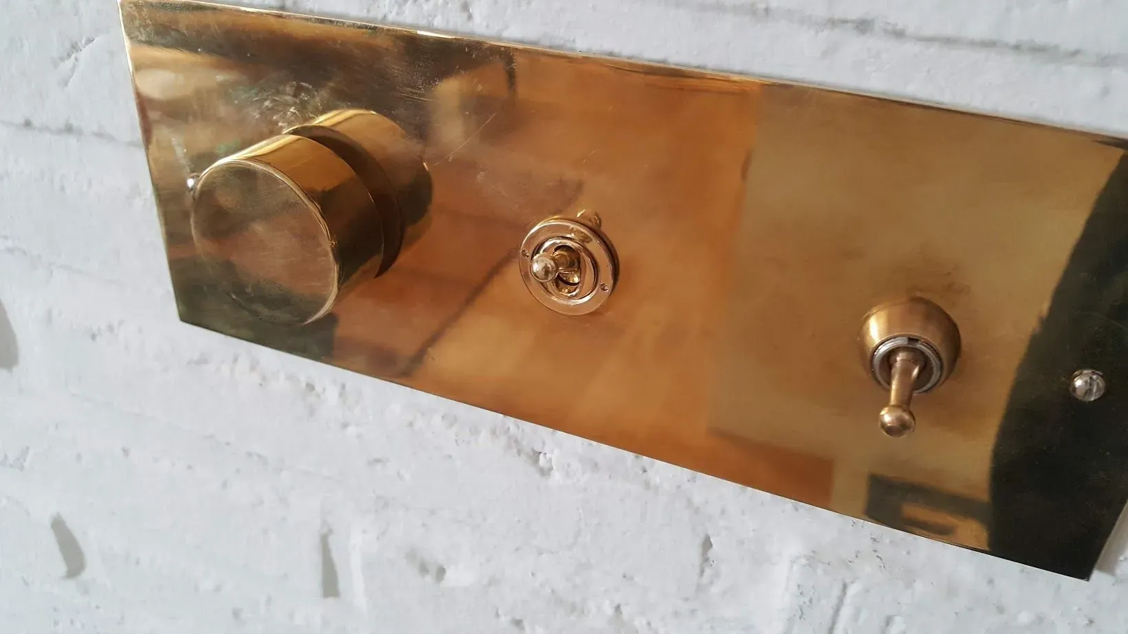 Un interruptor de luz de latón en una pared de ladrillos blancos
