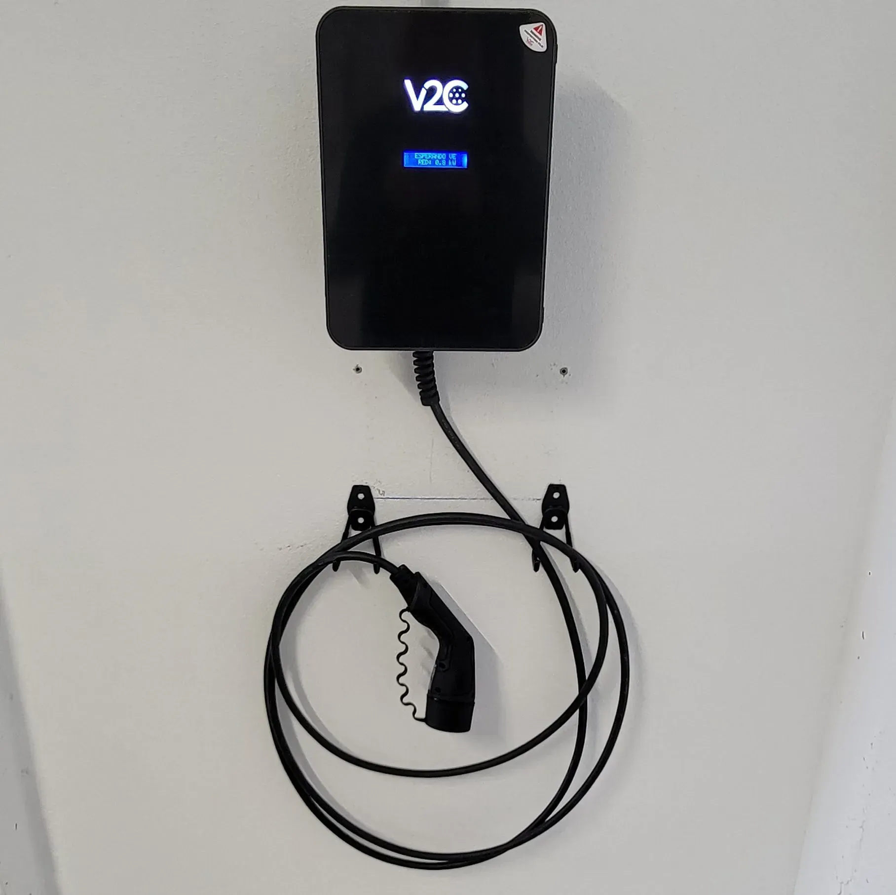 Un cargador v2c está conectado a una pared blanca.