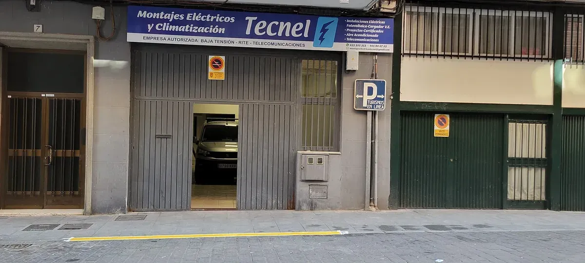 Un coche está aparcado delante de un edificio que dice tecnel
