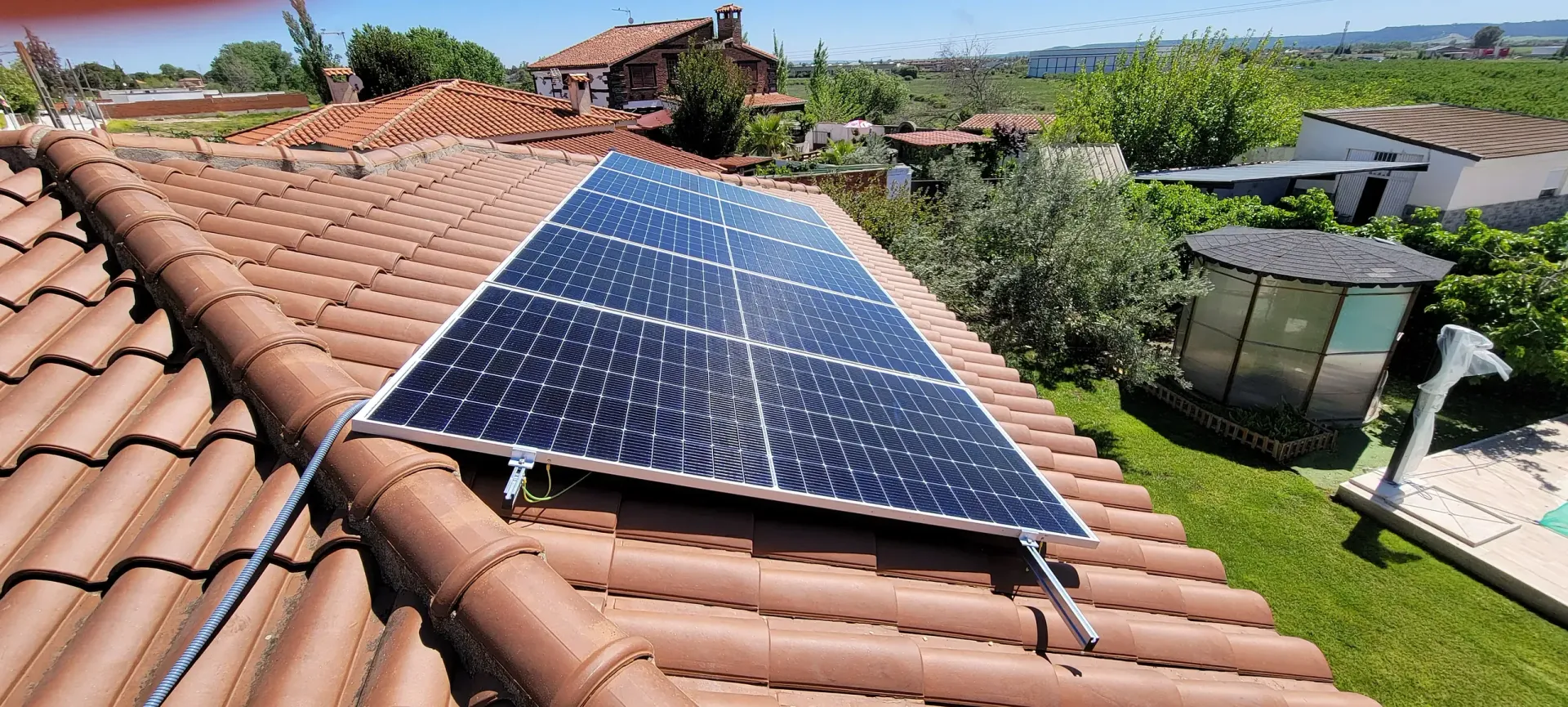 Un panel solar está situado encima de un techo de tejas.