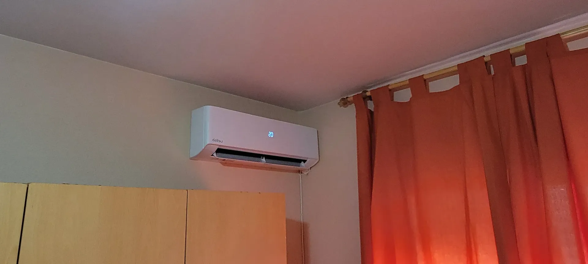 Una habitación con ventilador de techo y cortinas naranjas.