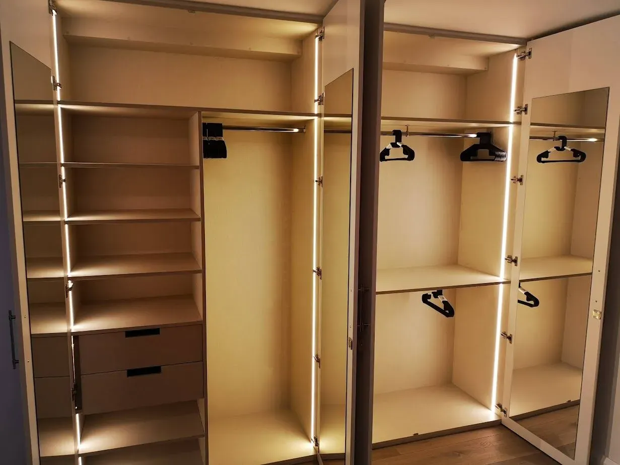 Un vestidor con espejo y perchas de ropa.