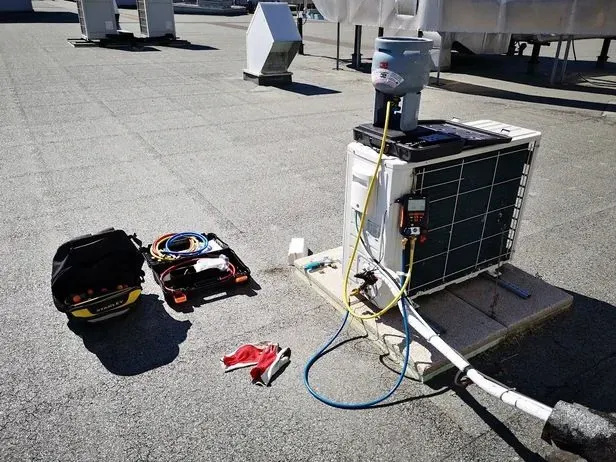 Se está realizando el mantenimiento de un aparato de aire acondicionado en el tejado de un edificio.