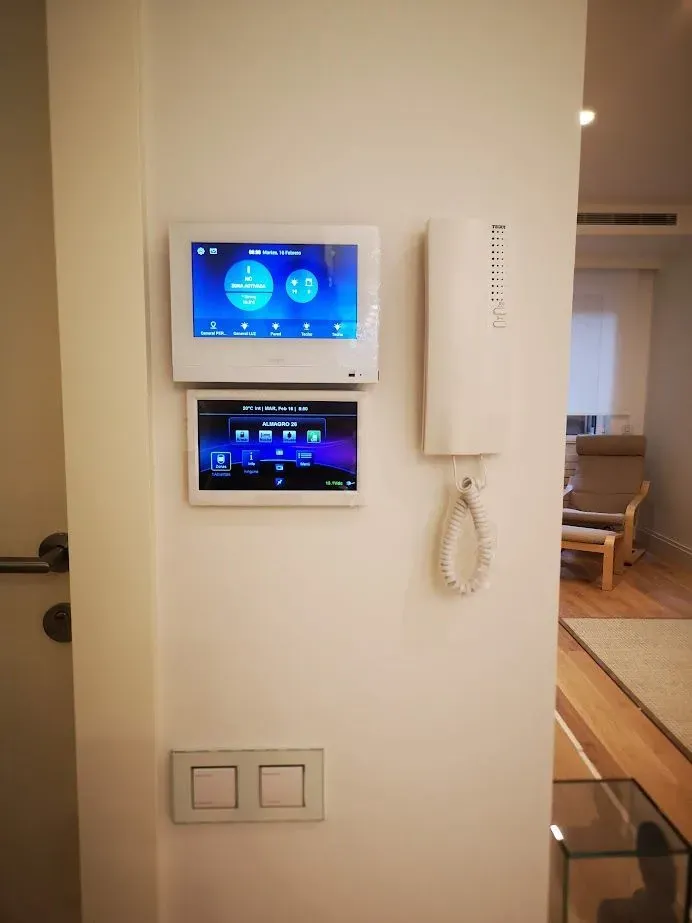 Una pared blanca con un teléfono y una tableta encima.