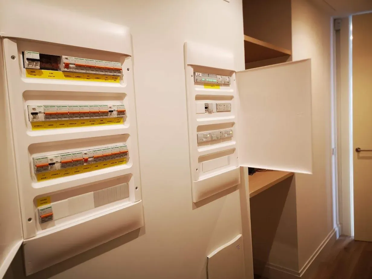 Dos cajas eléctricas están colgadas en una pared en un pasillo.