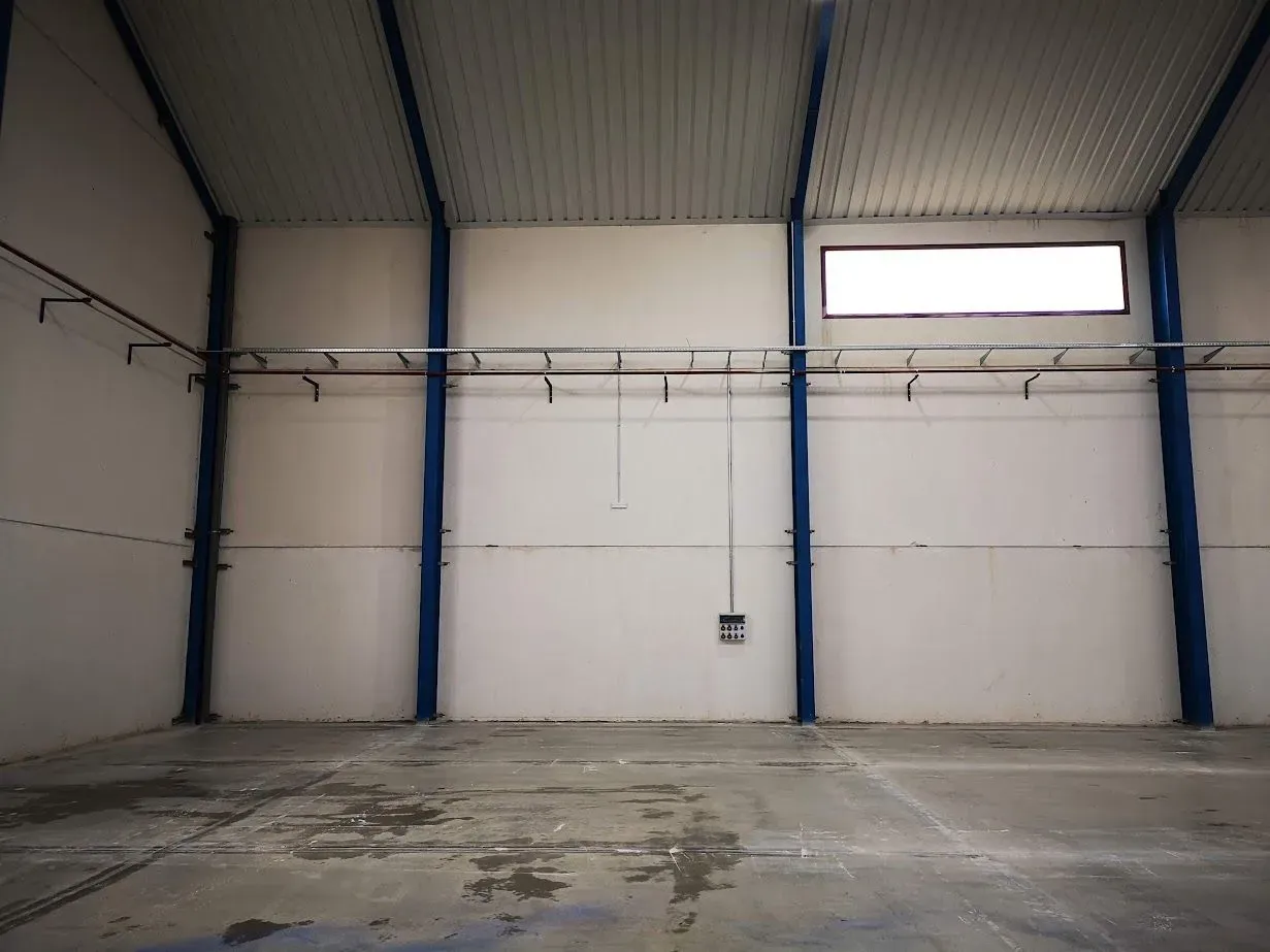 Un almacén vacío con paredes blancas y pilares azules.