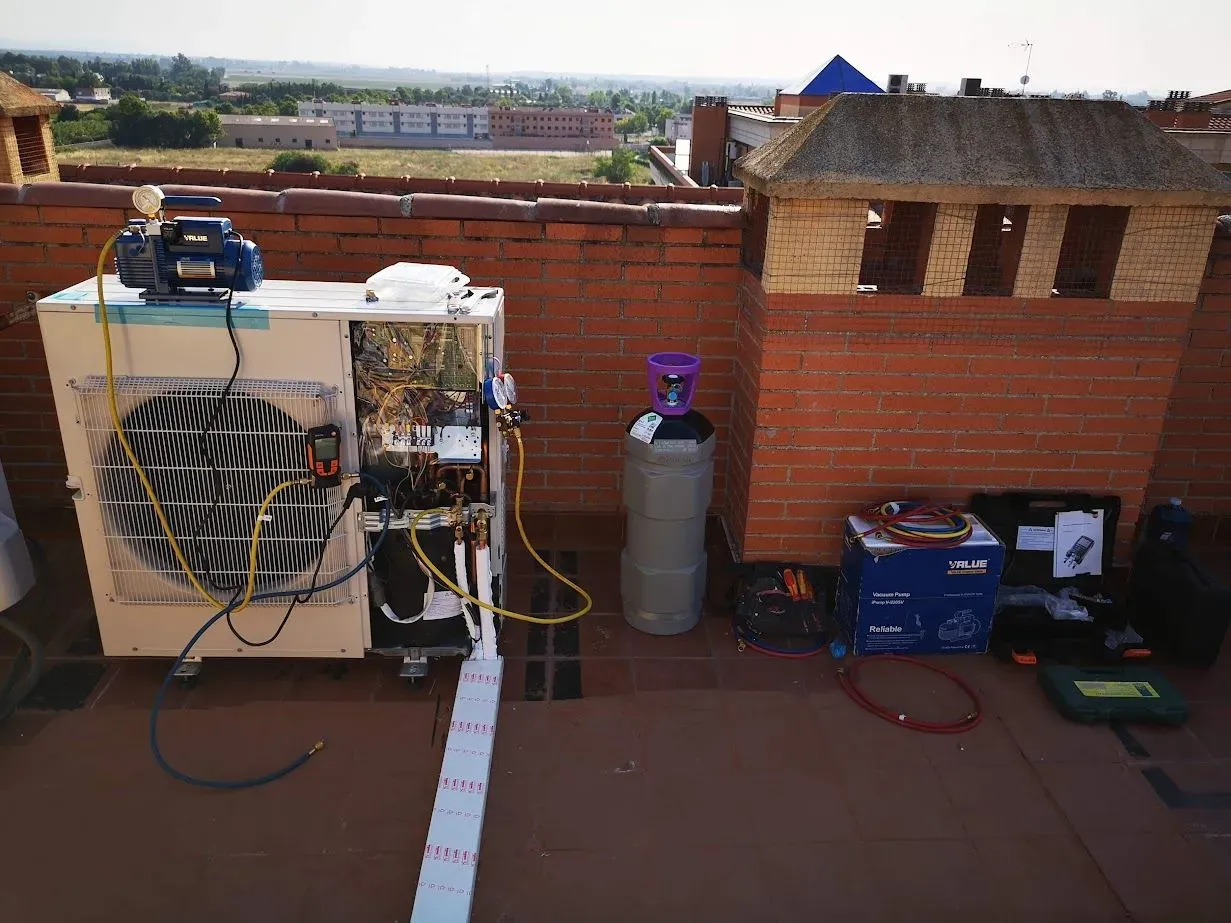 Se está reparando un aparato de aire acondicionado en el tejado de un edificio.