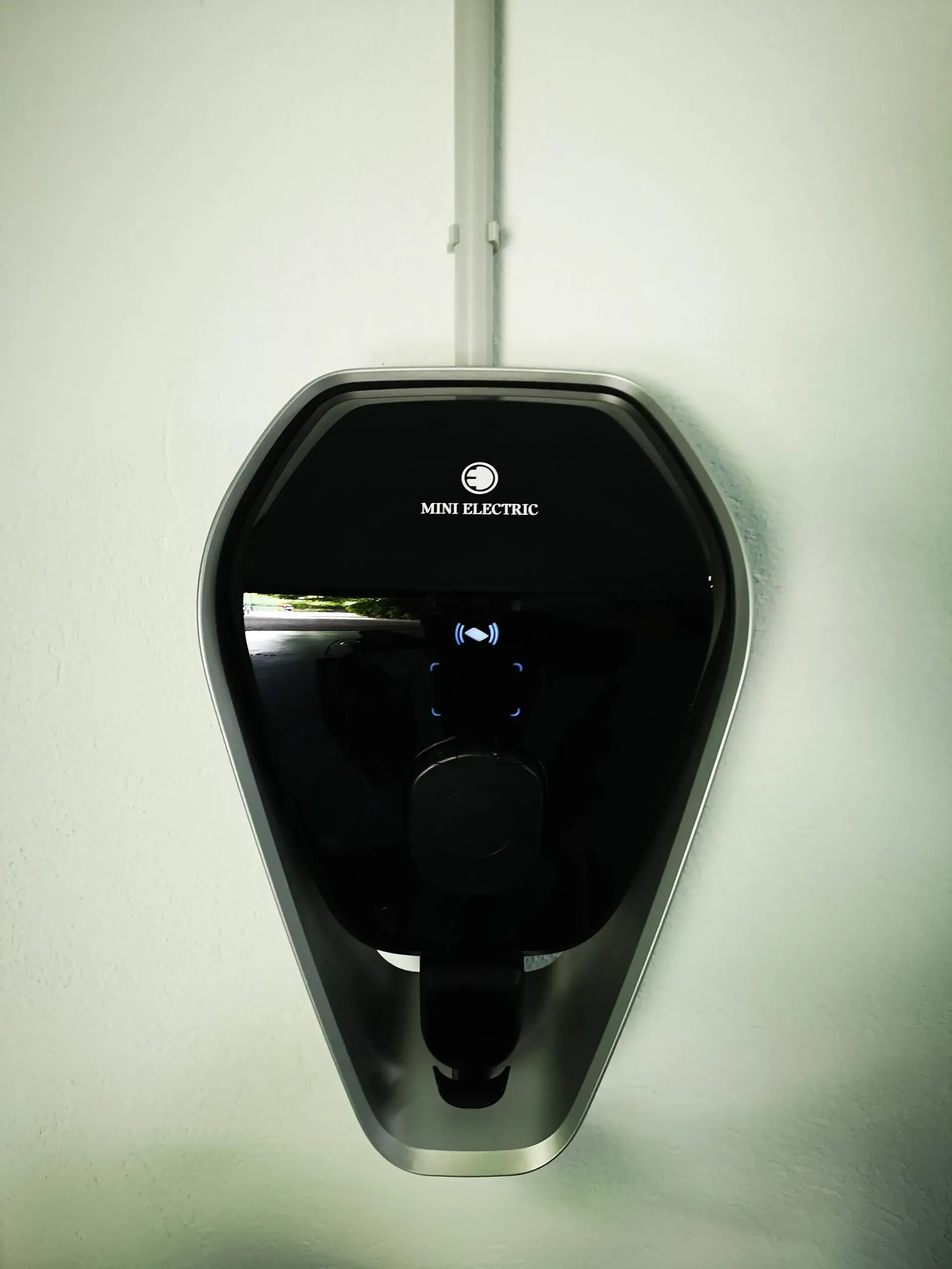 Un dispositivo negro está colgado en una pared blanca.