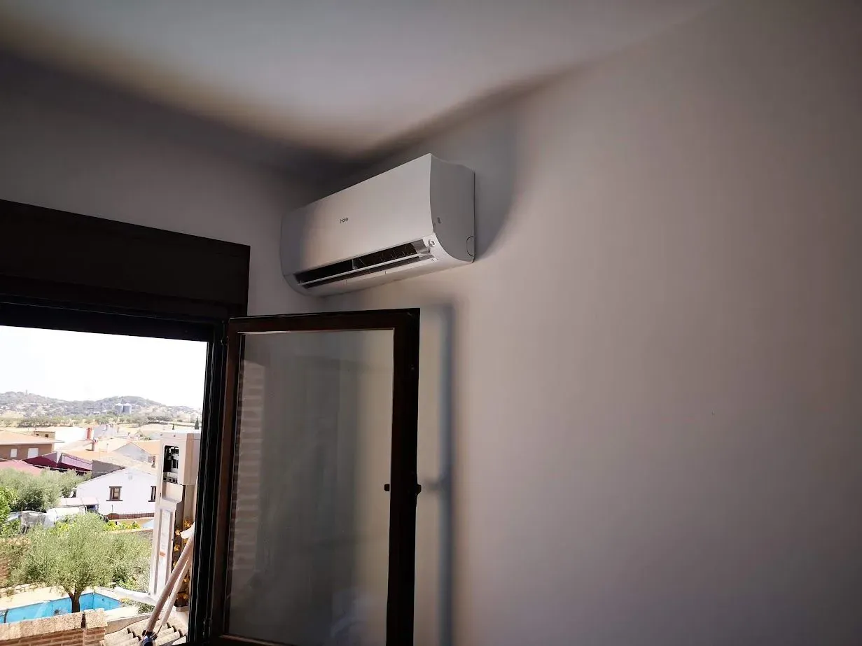 Una habitación con una ventana y un aire acondicionado en la pared.